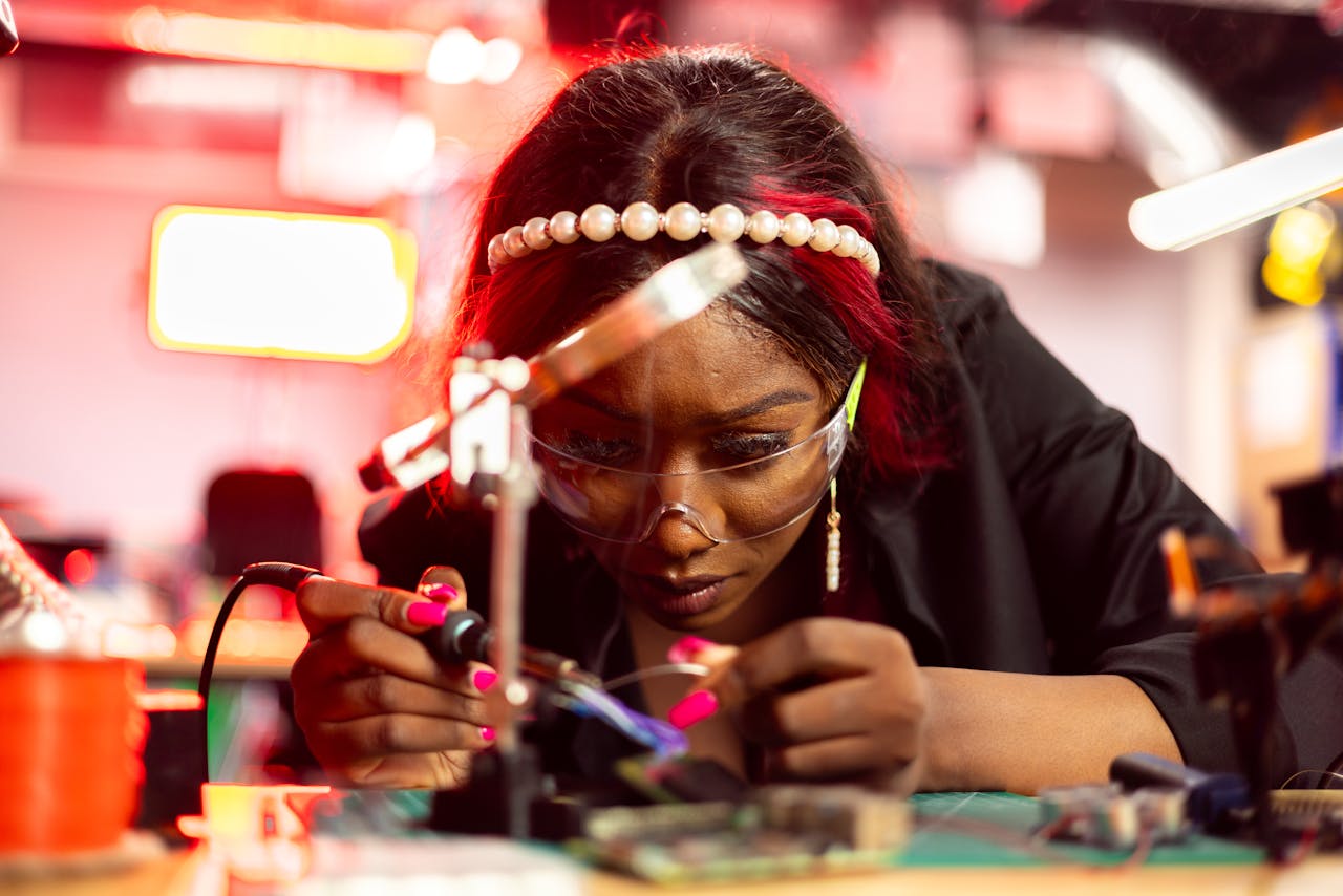 Woman intensely repairs electronics with precision tools and a soldering iron indoors.