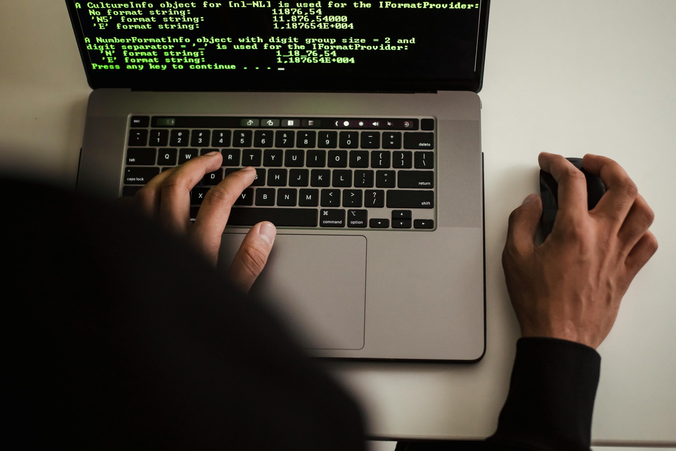 Close-up of a programmer typing on a laptop, displaying code on the screen.